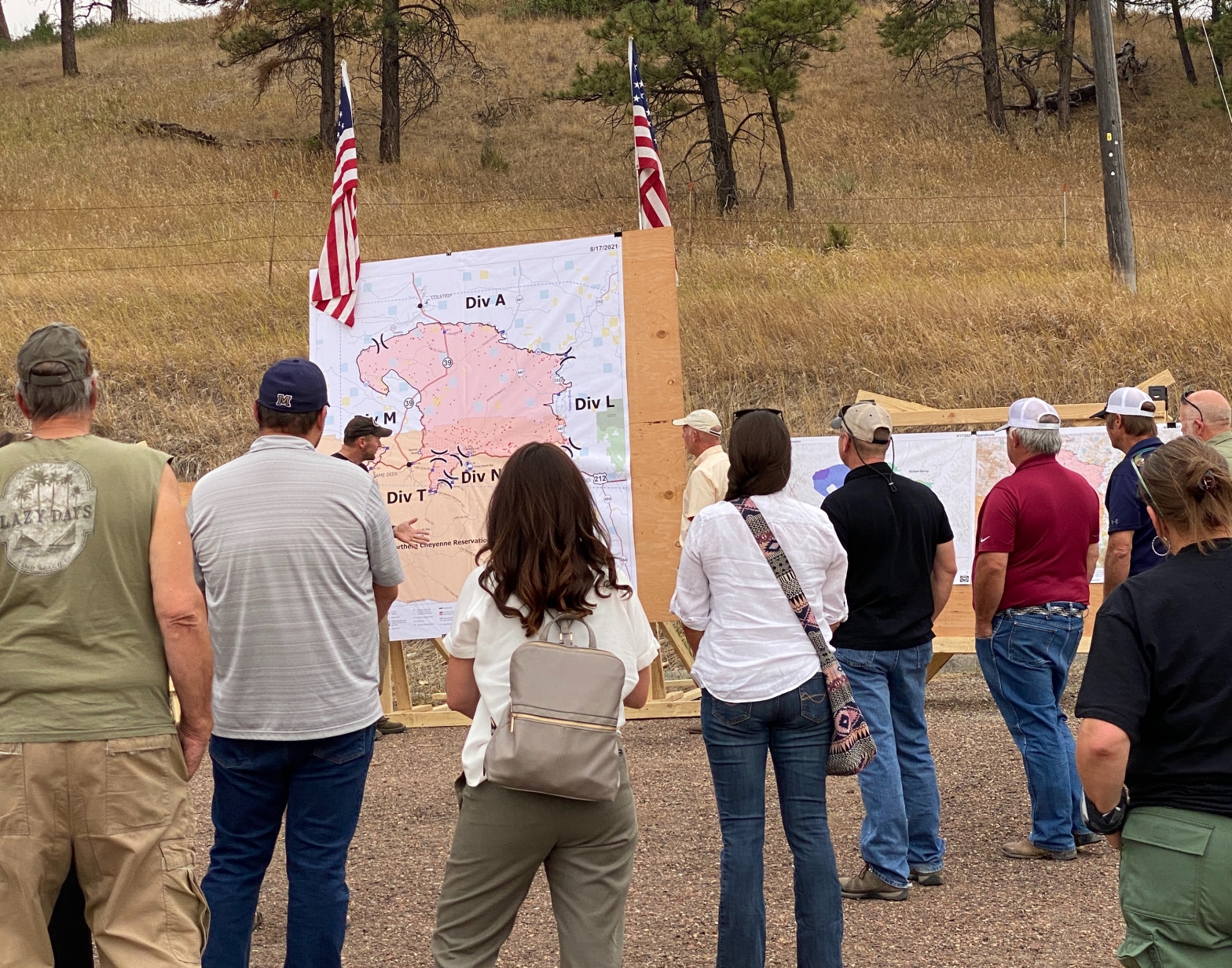Picture of a crowd and Governor being briefed on a wildfire in front of a huge map of the fire.